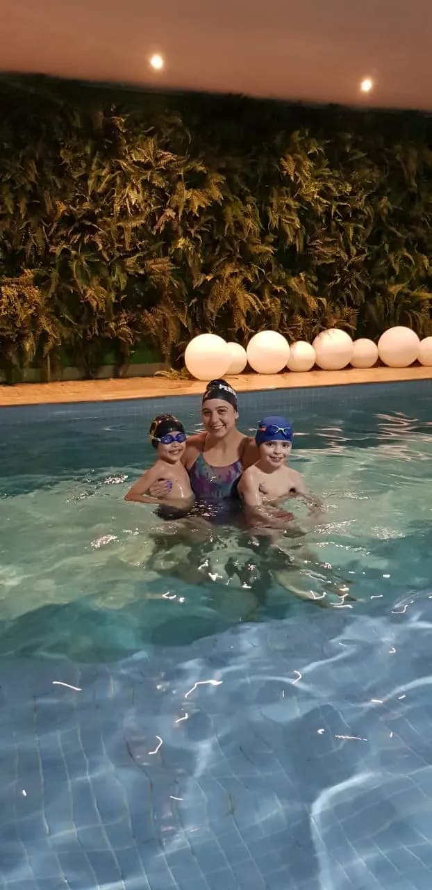Professora com duas crianças em aula na piscina coberta