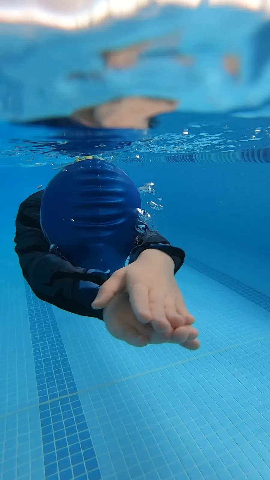 Nadador de touca azul deslizando debaixo d’água