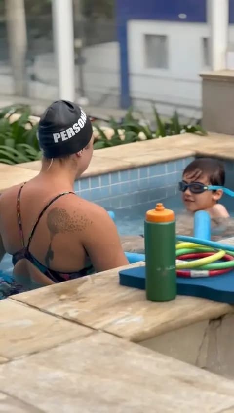 Instructor in a “Personal” cap guiding a child at the pool edge